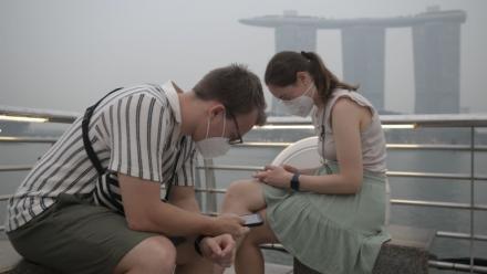 Des touristes portent des masques de protection contre les fumées générées par les incendies indonésiens, le 15 octobre 2026 à Singapour