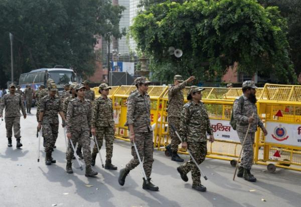 Les membres des forces de sécurité arrivent pour prendre leur poste à un point de contrôle temporaire à New Delhi, le 11 octobre 2026