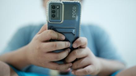 Bradley Rowen Liu, 11 ans, regarde une vidéo sur son téléphone le 25 mars 2026 à Jakarta, en Indonésie