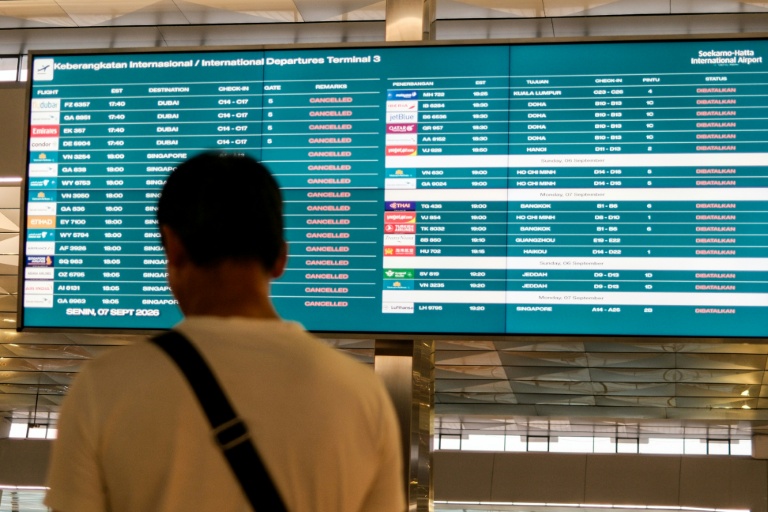 Un passager bloqué à l'aéroport international Soekarno-Hatta en raison de l'éruption du volcan Anak Krakatau, regarde un écran d'information sur les vols, le 7 septembre 2026 à Tangerang, en Indonésie