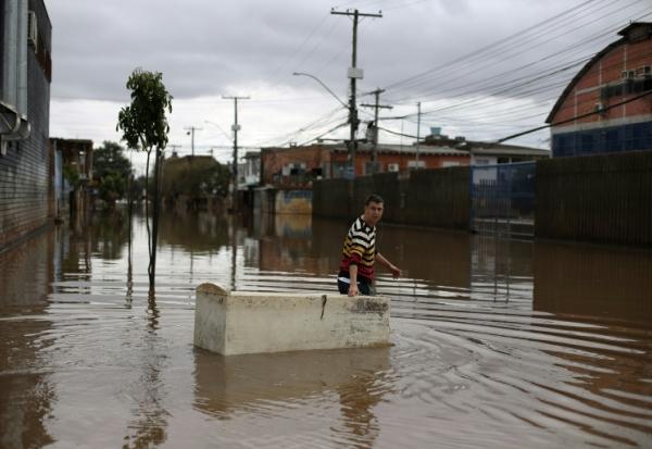 Un habitant utilise un réfrigérateur endommagé comme embarcation pour transporter des provisions dans une rue inondée de Porto Alegre, dans l'État de Rio Grande do Sul, au Brésil, le 26 mai 2024, pendant des inondations historiques dans le pays