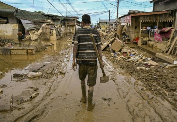 Un homme marche dans une rue couverte de boue après une crue soudaine qui a frappé la région d'Aceh Tamiang, dans la province d'Aceh, sur l'île indonésienne de Sumatra, le 6 décembre 2025