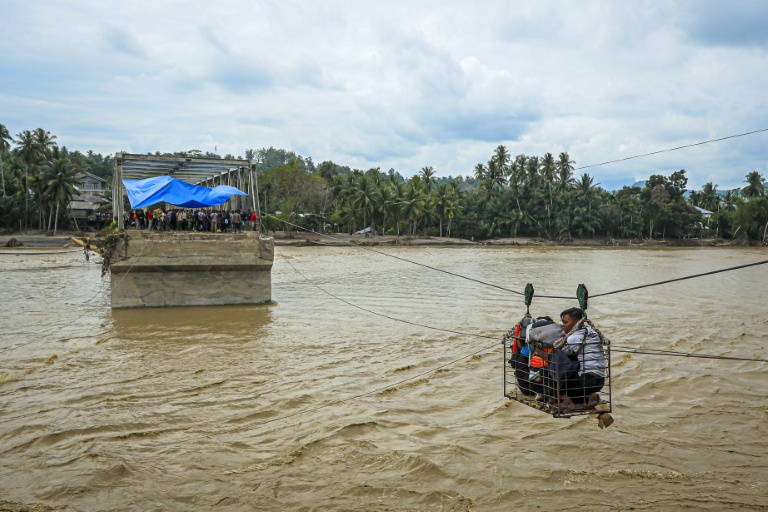 Des villageois utilisent une cabine sur câble pour traverser une rivière après la destruction d'un pont à Bireuen, en Indonésie, le 2 décembre 2025
