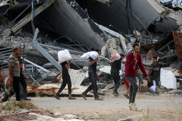 Des Palestiniens déplacés transportent des fournitures de secours distribuées par la Fondation humanitaire de Gaza (GHF), soutenue par les États-Unis, dans le centre de la bande de Gaza, le 8 juin 2025