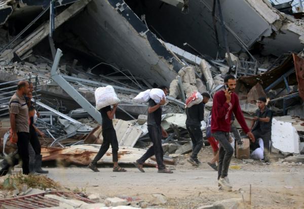 Des Palestiniens déplacés transportent des fournitures de secours distribuées par la Fondation humanitaire de Gaza (GHF), soutenue par les États-Unis, dans le centre de la bande de Gaza, le 8 juin 2025