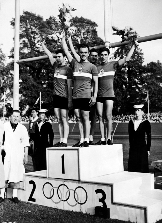 Charles Coste pose aux côtés de Pierre Adam, Serge Blusson et Fernand Decanali, sur la plus haute marche du podium des Jeux olympiques de Londres le 10 août 1948, après la victoire française à l'épreuve de poursuite par équipes