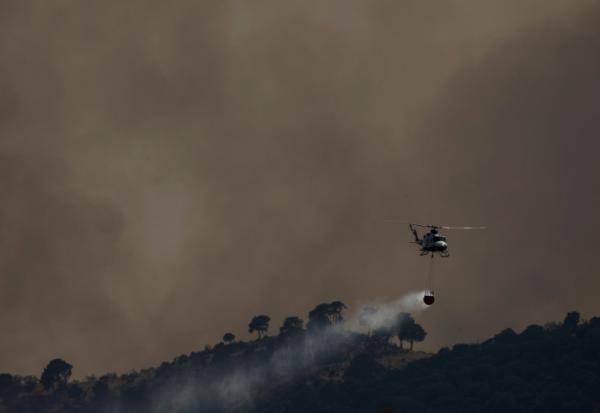 Un hélicoptère bombardier d’eau largue de l’eau sur un incendie de forêt près de Robledo de Chavela, à environ 60 kilomètres à l’ouest de Madrid, le 27 juillet 2026