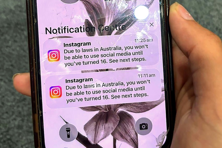Un adolescent tient un téléphone portable affichant un message du réseau social Instagram après que son compte a été verrouillé en raison de son âge, à Sydney, le 9 décembre 2025