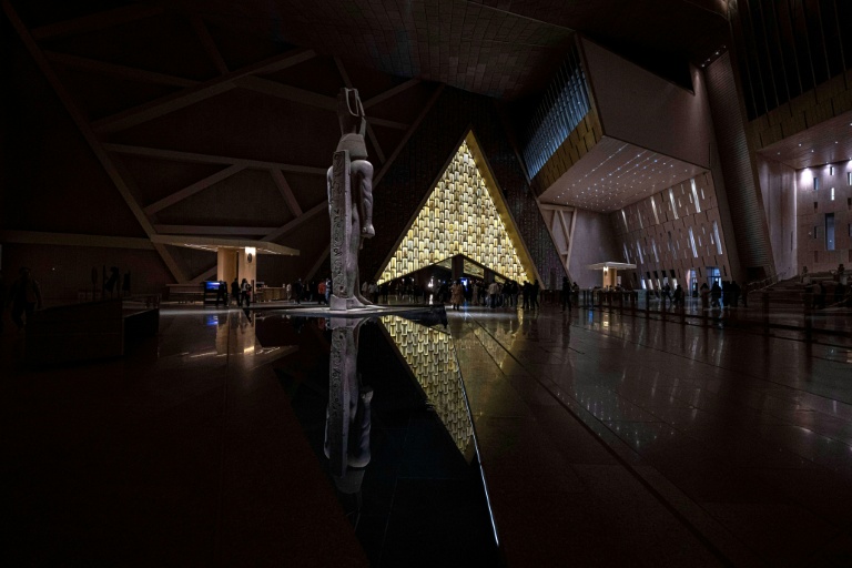 Des visiteurs déambulent près de la statue colossale du roi Ramsès II à l'entrée du Grand musée égyptien (GEM)  au Caire le 7 février 2025, avant l'ouverture officielle