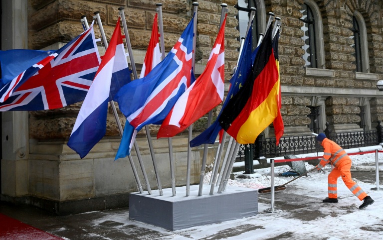 Un ouvrier déblaye la neige devant la mairie, l'un des lieux où se tient le Sommet de la mer du Nord, le 26 janvier 2026 à Hambourg, dans le nord de l'Allemagne.