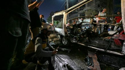 Des passants et des secouristes inspectent la carcasse du minibus dans lequel une bombe a explosé, à Jaramana, près de la capitale syrienne, Damas, le 6 août 2026