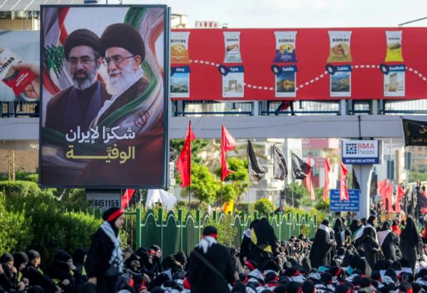 Une affiche représentant le défunt ayatollah Ali Khamenei et son fils l'actuel guide suprême iranien Mojtaba Khamenei est exposée alors que des fidèles chiites se rassemblent pour une procession funèbre, dans la banlieue sud de Beyrouth, le 26 juin 2026