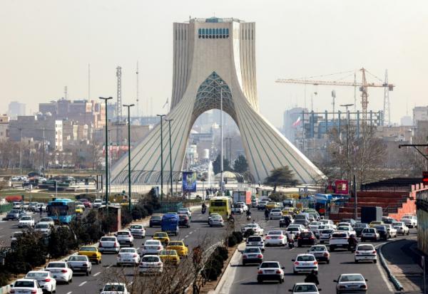 Des véhicules circulent sur une autoroute près de la célèbre Tour Azadi à Téhéran le 23 février 2026