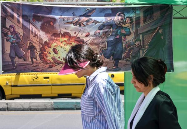 Une Iranienne passe devant une banderole représentant l'attaque américano-israélienne contre l'Iran, dans la capitale Téhéran, le 9 mai 2026