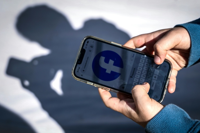 Un adolescent consulte Facebook sur son téléphone portable, le 24 octobre 2025 à Gosford, en Australie
