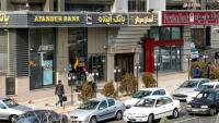 Des Iraniens passent devant une succursale de la banque Ayandeh (G) dans la capitale Téhéran, le 14 janvier 2017