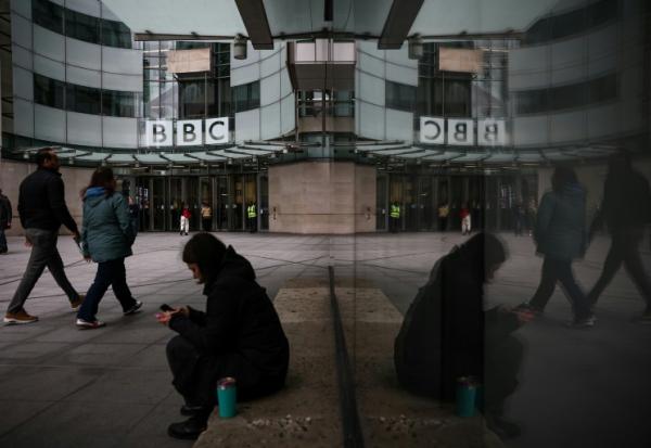 Des passants marchent devant l'entrée des bureaux de la BBC à Londres le 11 novembre 2025
