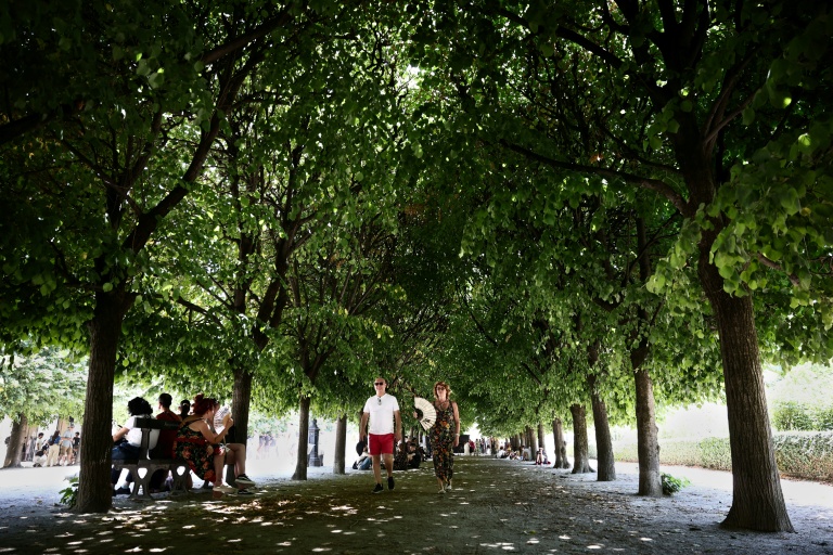Des piétons marchent à l'ombre tout en s'éventant pour se rafraîchir lors d'une vague de chaleur au Jardin du Palais-Royal à Paris, le 21 juin 2026