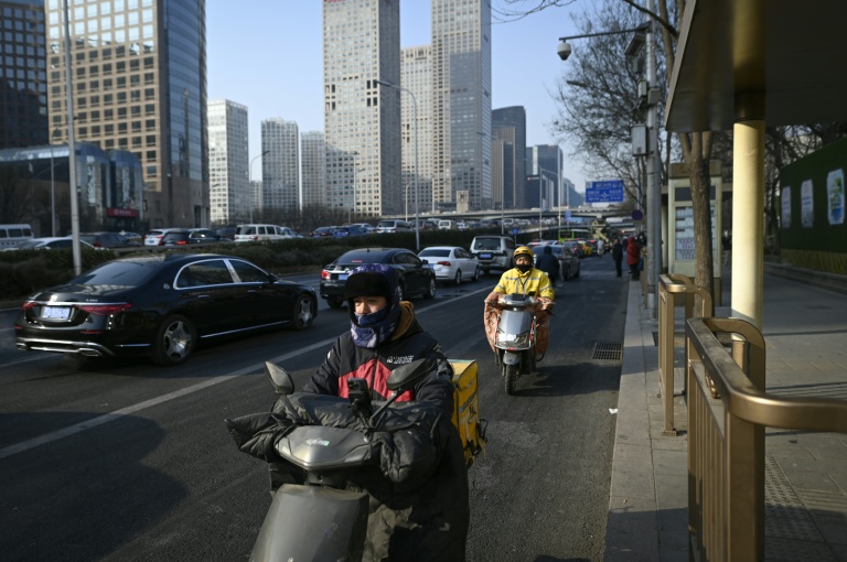 Des livreurs de repas conduisent des scooters électriques à Pékin, le 16 janvier 2024