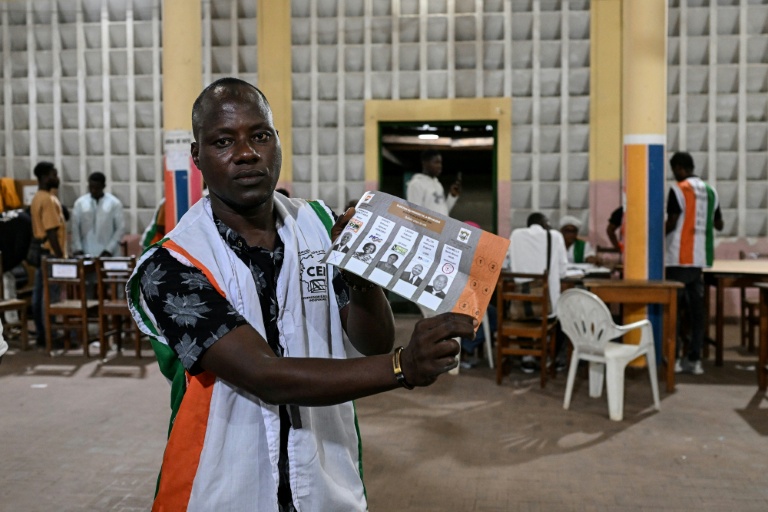 Un représentant de la commission électorale montre un bulletin de vote pour la présidentielle ivoirienne, à Abidjan le 25 octobre 2025