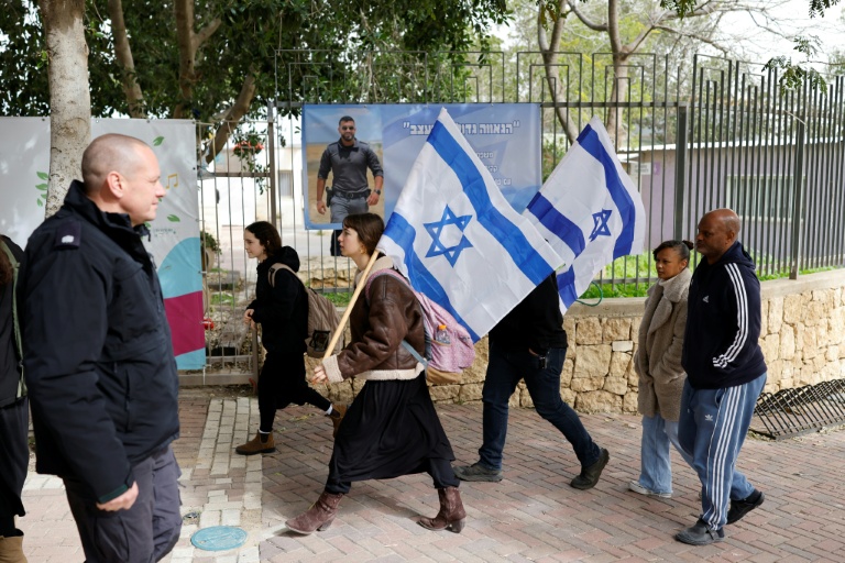 Des personnes portant des drapeaux israéliens se dirigent vers les funérailles de l'otage Ran Gvili, à Meitar, le 28 janvier 2026