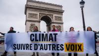 Des militants tiennent une banderole "Climat, écoutez les autres voix" lors d'une action de Greenpeace devant l'Arc de Triomphe à Paris, le 12 décembre 2025, à l'occasion du 10e anniversaire de la signature des accords de Paris sur le climat