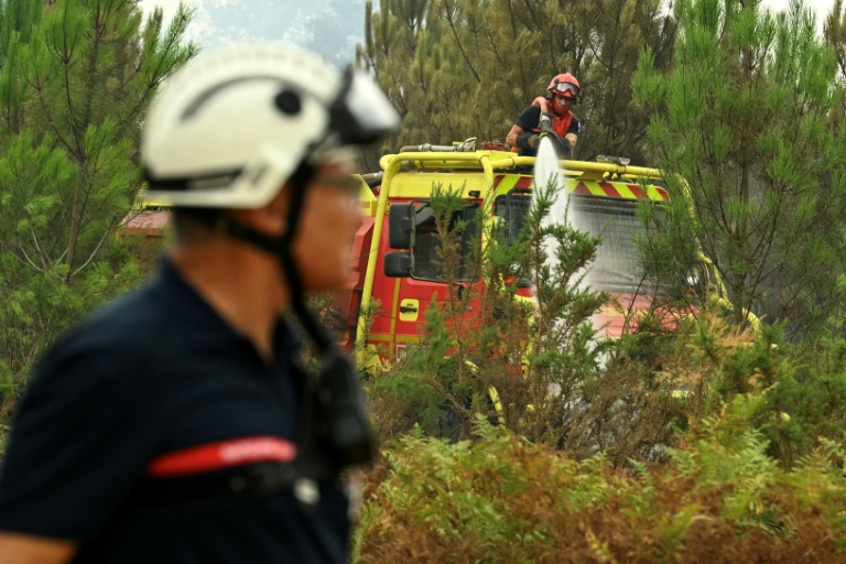 Des pompiers arrosent de la végétation pour éviter une reprise de feu près de Luglon, dans les Landes, le 15 août 2026