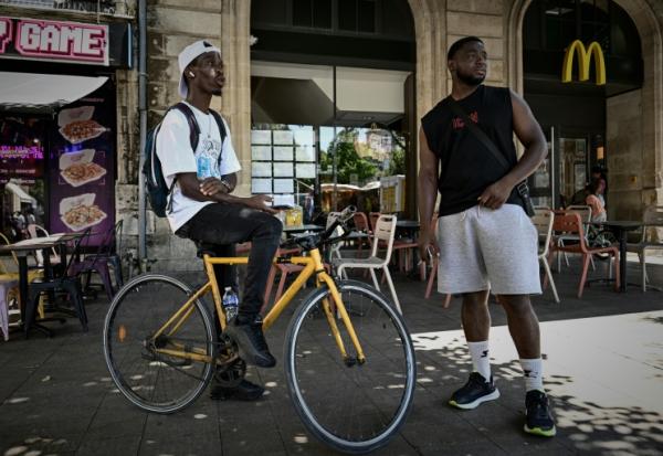 Deux livreurs à vélo se reposent pendant une vague de chaleur estivale près des restaurants en attendant des commandes, à Bordeaux, le 7 juillet 2026