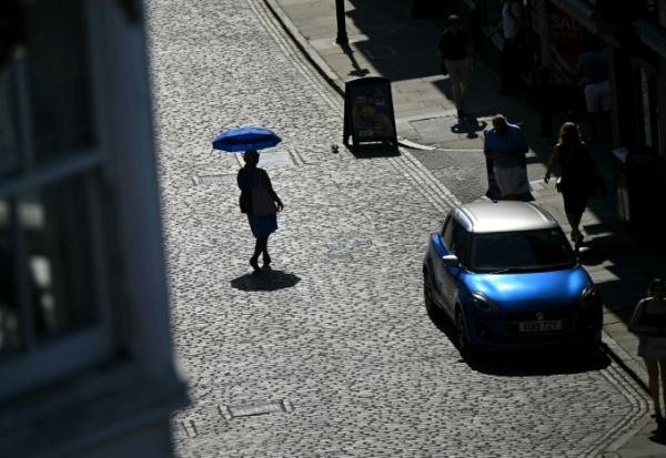 Une personne se protège du soleil sous une ombrelle, le 25 juin 2026 à Guildford, au Royaume-Uni, lors d'un épisode de canicule en Europe