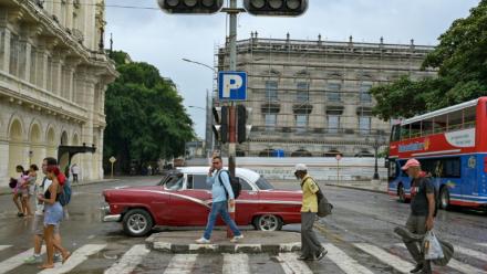 Des piétons traversent devant un feu de signalisation éteint en raison d'une panne d'électricité dans une rue de La Havane, le 3 décembre 2025