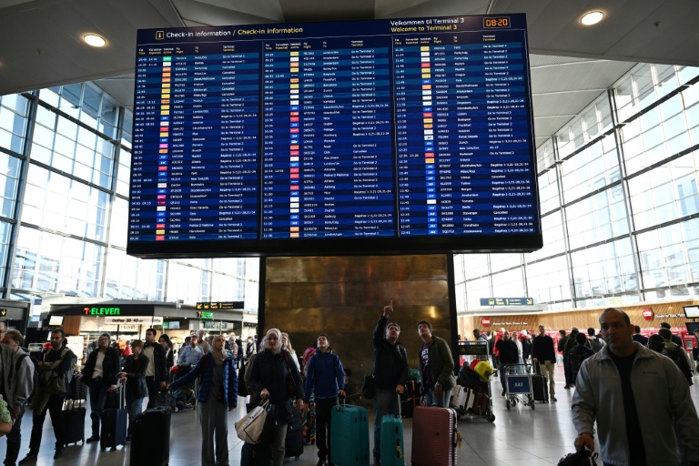 Des voyageurs consultent un panneau d'information sur les vols à l'aéroport de Copenhague, après un survol de drones, le 23 septembre 2025 au Danemark