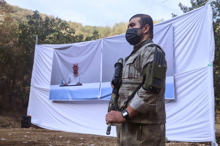 Un combattant du PKK devant un portrait d'Abdullah Öcalan, lors d'une cérémonie à Kandil, dans le nord de l'Irak, le 26 octobre 2025