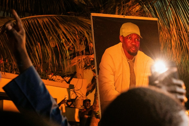 Des partisans d'Ousmane Sonko brandissent son portrait devant son domicile de Dakar, le 23 mai 2026