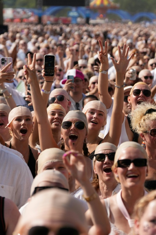 Des fans du rappeur américain Pitbull portent de faux crânes chauves avant un concert de l'artiste, le 10 juillet 2026 à Londres 