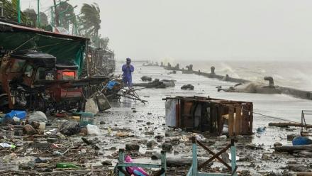 Un homme se tient à côté de débris près du bord de mer, le 22 septembre 2025 à Aparri aux Philippines
