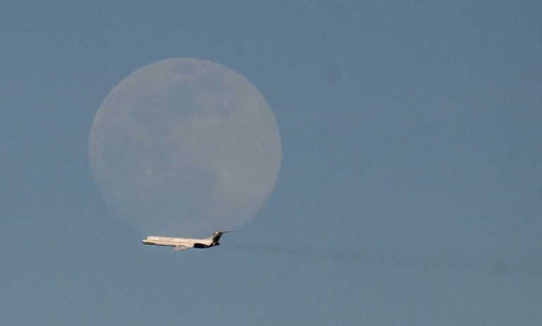 Un avion de la compagnie vénézuélienne Rutaca passe devant la lune, vu depuis l'aéroport international Simon Bolivar à Maiquetia, Venezuela, le 3 décembre 2025