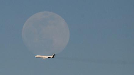 Un avion de la compagnie vénézuélienne Rutaca passe devant la lune, vu depuis l'aéroport international Simon Bolivar à Maiquetia, Venezuela, le 3 décembre 2025