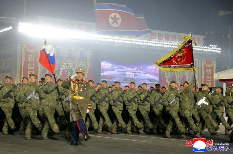 Photo prise le 25 février 2026 et diffusée le 26 février 2026 par l'agence de presse officielle nord-coréenne KCNA, montrant des soldats envoyés en Russie défilant sous le drapeau russe lors des commémorations du 9e Congrès du Parti des travailleurs de Corée, place Kim Il-sung à Pyongyang