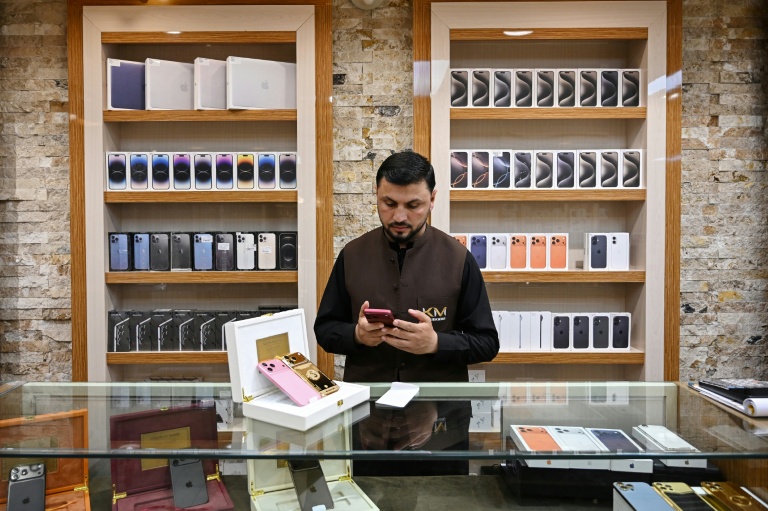 Un vendeur utilise un smartphone en attendant des clients dans un magasin à Kaboul, le 10 août 2026 en Afghanistan