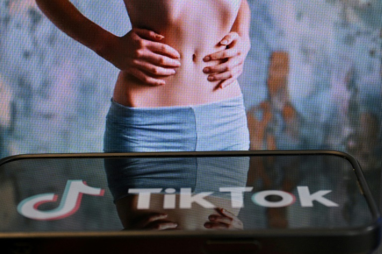 Photo d'illustration du 7 mai 2025 montrant le logo de Tik Tok sur un smartphone devant un écran affichant l'image d'une femme très mince, alors que la tendance