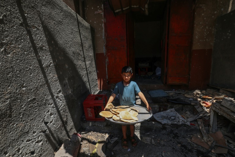 Un garçon palestinien sort avec du pain d'une boulangerie de fortune touchée par des frappes israéliennes dans le camp de réfugiés de Nusseirat, dans le centre de la bande de Gaza, le 8 mai 2025