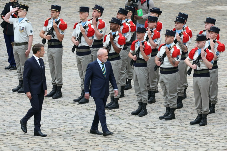 Le président français Emmanuel Macron (g) ry son homologue brésilien Luiz Inácio Lula da Silva passent en revue la Garde d'honneur lors d'une cérémonie à l'hôtel des Invalides, le 5 juin 2025 à Paris