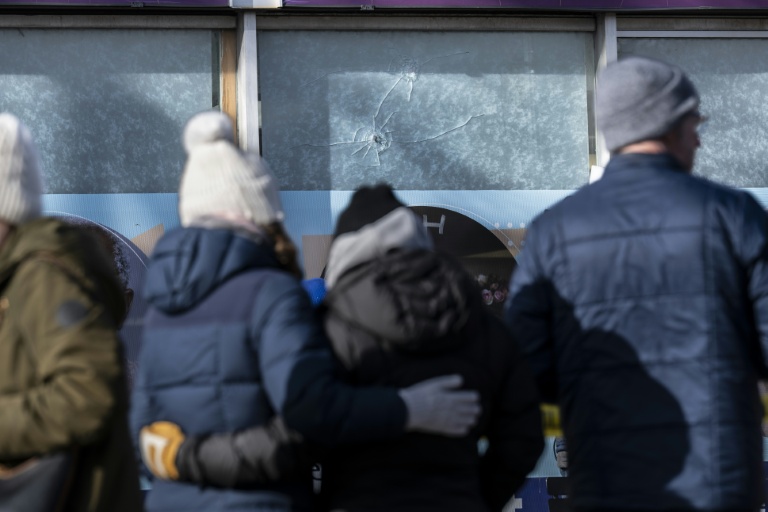 Recueillement à Minneapolis, dans le Minnesota, le 26 janvier 2026, devant des impacts de balles dans la vitrine d'un commerce sur les lieux de la mort d'Alex Pretti, décédé deux jours plus tôt