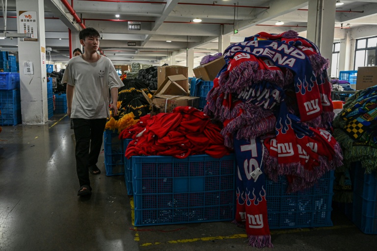 Un employé passe devant une pile de produits dans une usine qui fabrique des chapeaux et des écharpes à Yiwu, dans la province du Zhejiang, dans l'est de la Chine, le 18 septembre 2025