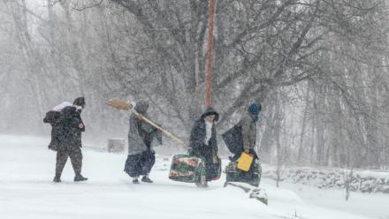 Des habitants marchent sous la neige avec leurs effets personnels sur une route de dans la province afghane de Parwan, dans l'est du pays, le 21 janvier 2026 