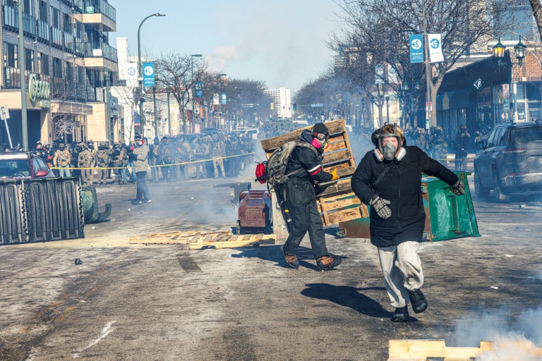 Des manifestants devant une barricade d'agents américains des forces de l'ordre fédérales après la mort d'un homme de 37 ans, tué par balle par des agents fédéraux, à Minneapolis (Minnesota), le 24 janvier 2026