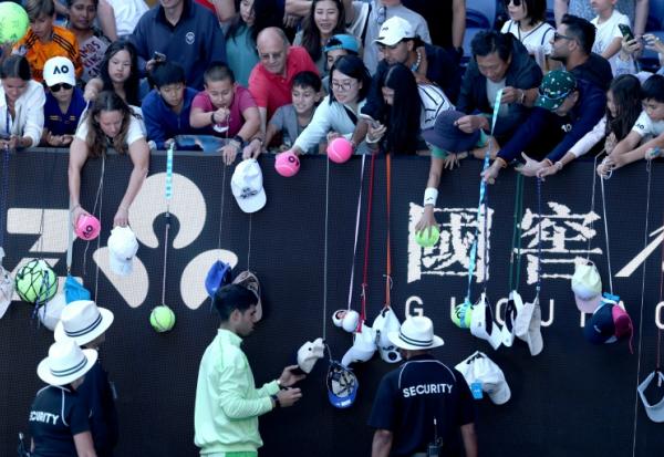 L'Espagnol Carlos Alcaraz (en bas) signe des autographes après avoir battu le Français Corentin Moutet au troisième tour de l'Open d'Australie, à Melbourne, le 23 janvier 2026