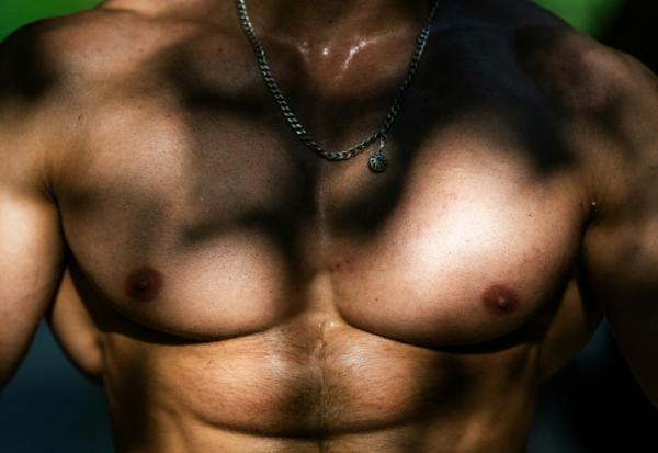 Le torse musclé d'un homme qui s'entraîne sur une aire de street workout à Paris, le 10 août 2025