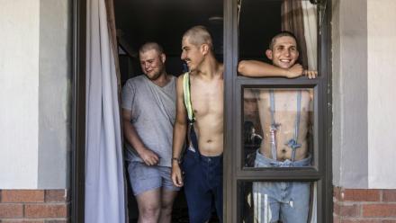 Des étudiants, Belly Sharpe (C), 18, et Eben Mans (D), 20, rient avec un ami à l'entrée de leur dortoir Vaalbos dans l'enclave afrikaner d'Orania en Afrique du Sud, le 28 janvier 2026.