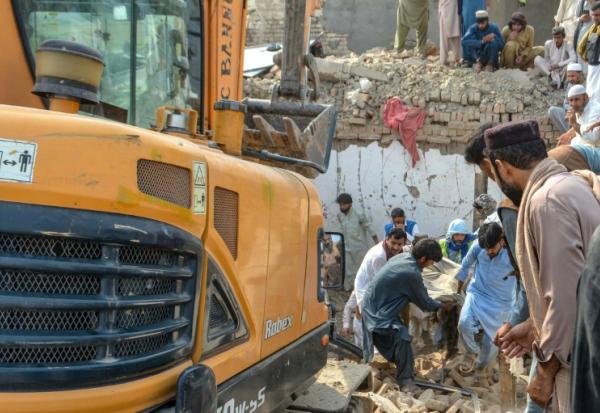 Des personnes transportent le corps d'une victime après un attentat contre un poste de contrôle de police à Bannu, dans le nord-ouest du Pakistan, le 10 mai 2026